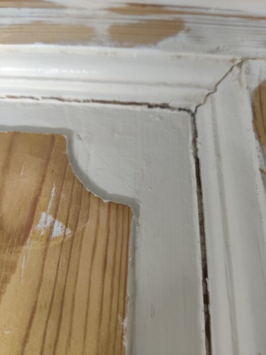 Skarvar i träpanel med vit färg som delvis flagnat och synligt trä, diskussion om att undvika sprickor vid ommålning.