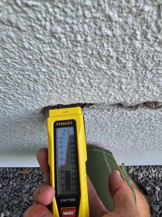 Gul fuktmätare visar 23% på sprucken puts.