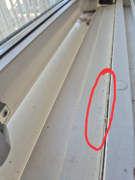 Fönsterkarm med skrapmärken mitt på, markerat med röd cirkel, visar problemet med att fönstret inte går att stänga.
