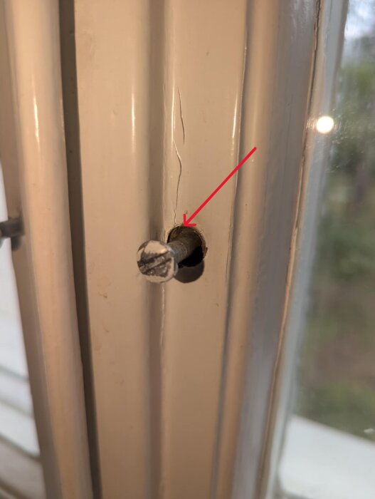 Närbild av en skruv och hylsa i fönsterbåge, med en röd pil som pekar på hylsan där skruven roterar utan att få grepp.