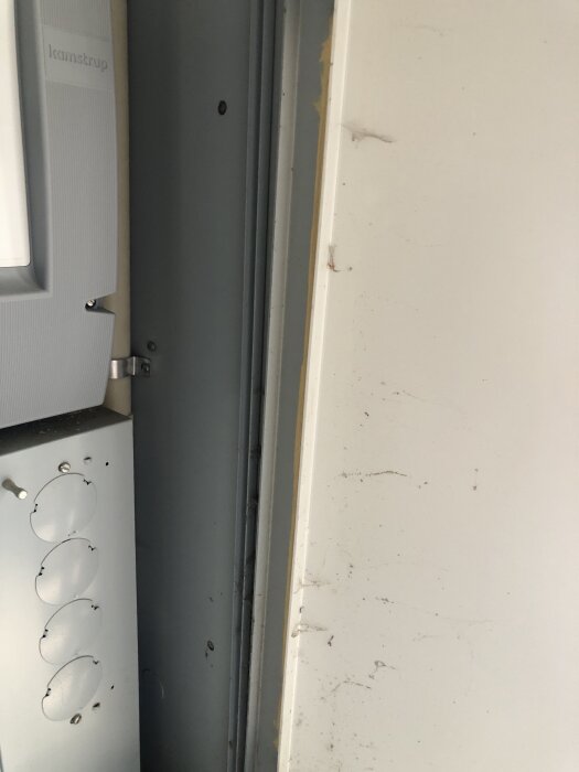 En elcentral från Omipower med en plåtlåda infälld i en tegelvägg, synliga detaljer inkluderar fyra täckta genomföringar och en stängd panel.