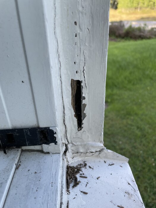 Rötskadat fönsterfoder med sprucken färg och synlig skada, visas på närbild med utsatt område tydligt i bild.