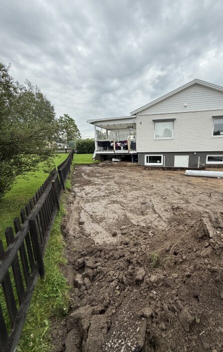 Uppfart grävd till rätt nivå, med borttagen mark och gräs. En vit villa och staket i bakgrunden. Klar yta för vidare renovering.