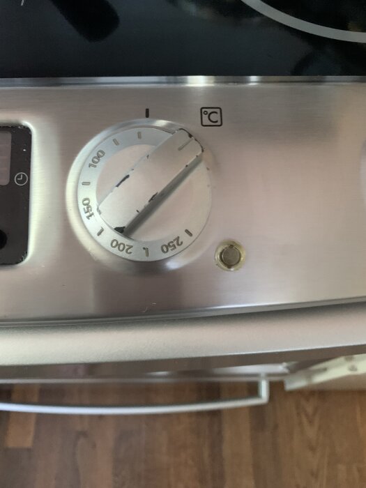 Ugnens termostatvred inställt på 150°C med termostatlampa bredvid på en spis.
