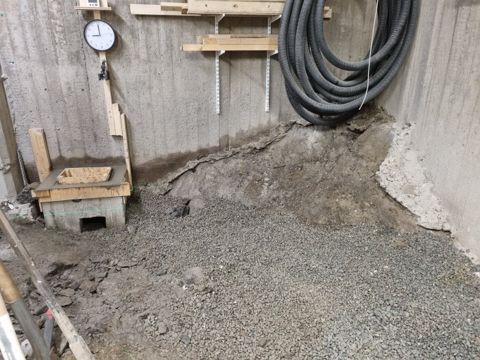 Ren och städad byggarbetsplats med borttagna stenar, nyligen gjuten yta, klocka och kablar på betongvägg.