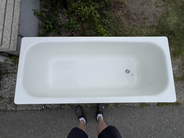 Gammalt badkar i plåt 160x70 cm med bottenventil, står utomhus på betong, syns från ovan.