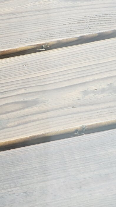 Trätrall med inbyggda skruvhål och vissa synliga skruvhuvuden efter montering, märkbara variationer efter torkning och svällning av träet.