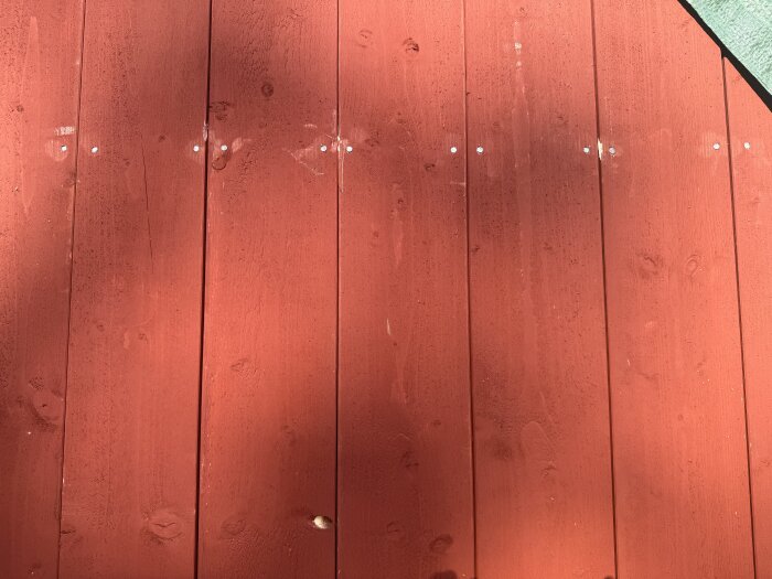 Röd träpanel på 1800-talshus med tättsittande brädor utan mellanrum.