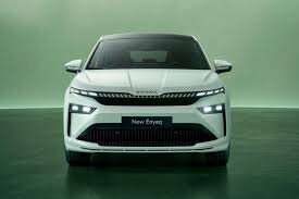 Vit Skoda Enyaq med ny grilldesign, frontvy på grön bakgrund.