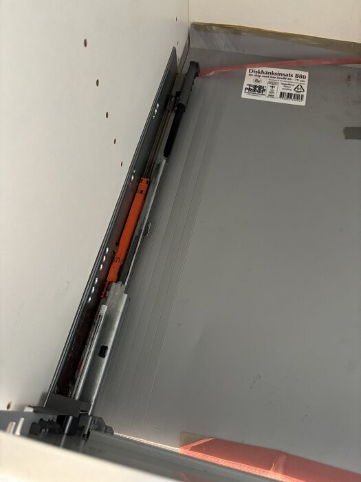 Lådfront från Myresjökök monterad på en skena intill en diskmaskin, visas inifrån ett köksskåp.