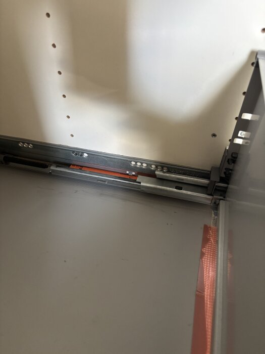 Lådfront mot diskmaskin i köksskåp, justeringsproblem på grund av skav under installation, fokus på skensystem och infästning inuti skåpet.