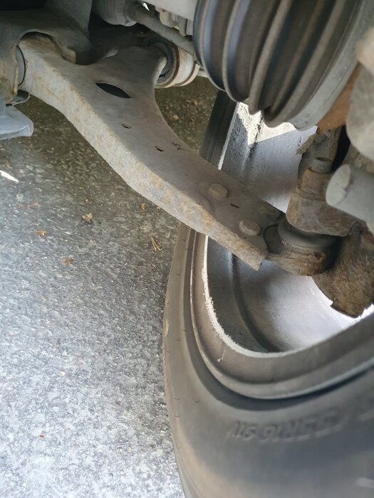 Närbild på bilens framdel med fokus på hjulupphängning och styrled, visar däckets kant och delar av hjulhuset.