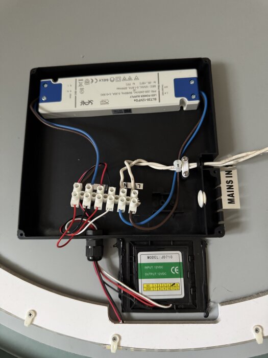 Elektrisk kopplingsbox med kablar och en transformator, del av en spegelinstallation som styrs av en touchknapp.