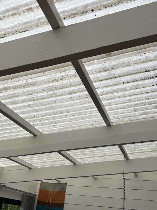 Altan med vitt trätakstol och korrugerat plasttak, diskussion om fuktproblem och möjliga lösningar som plåt eller kanalplast.