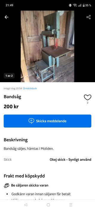 Blå bandsåg i träverkstad med träväggar i bakgrunden. Prislapp på 200 kronor syns i annonsen.