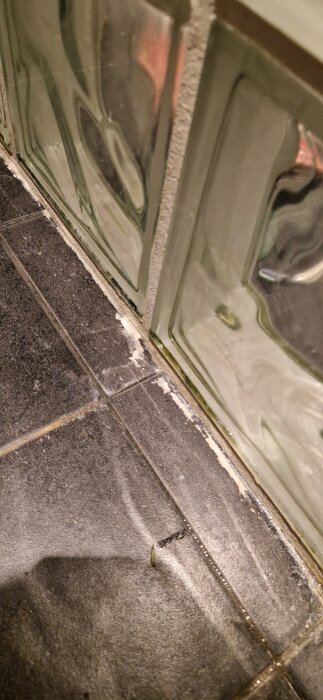 Bild på kakel och fogar med vita kalkavlagringar och smuts som sitter fast; försökt rengöras utan framgång.