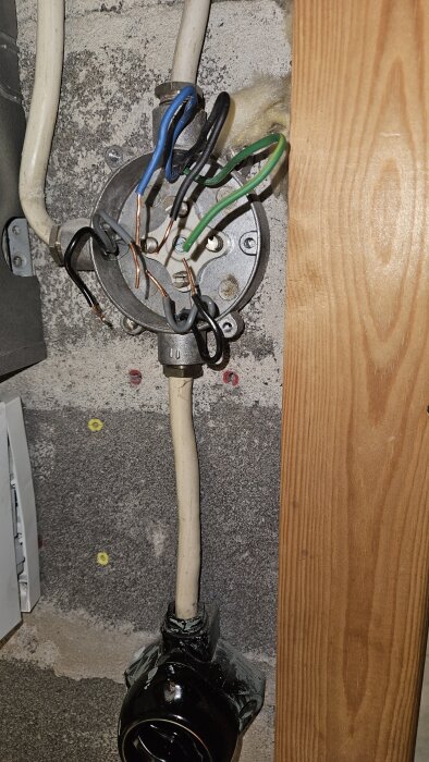 Elektrisk kopplingsdosa monterad på vägg med flera exponerade kablar och ledningar, förberedd för installation av rörelsesensor i tvättstuga.