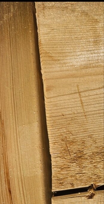 Träplankor med sprickor och ojämn kant, tecken på dåligt hantverk eller skador som behöver åtgärdas.