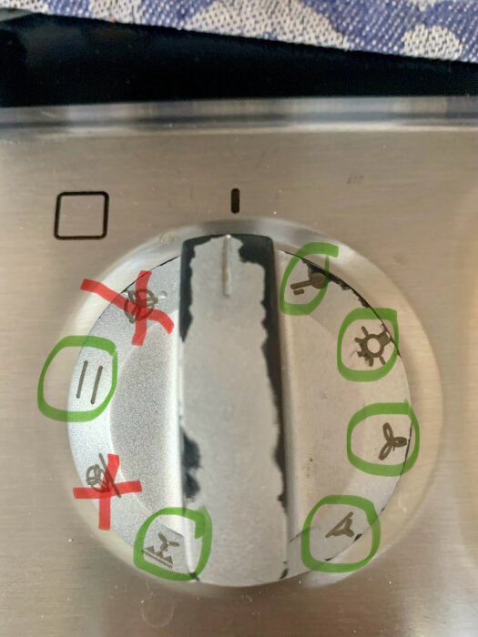 Ugnsvred med symboler och markeringar i grönt och rött för olika funktioner som avstängning, värme och fläkt.