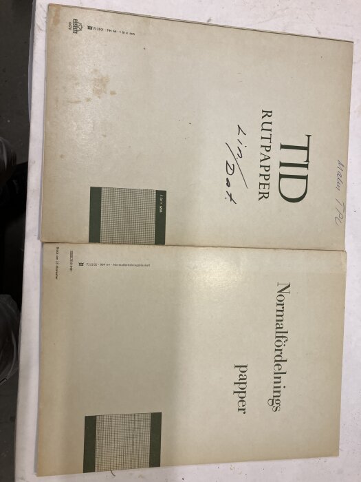 Två ark av TID rutpapper och Normalfördelningspapper, liggande på ett bord.