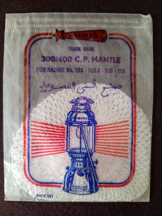 Förpackning med glödstrumpa för Primuslykta, märkt med "300/400 C.P. Mantle" och illustration av en lykta, text på engelska och arabiska.