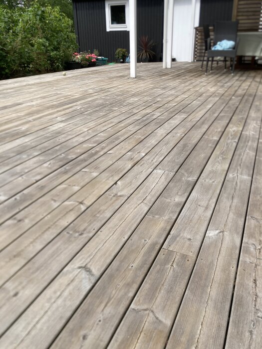 Stor träaltan med utemöbler och växter i bakgrunden.