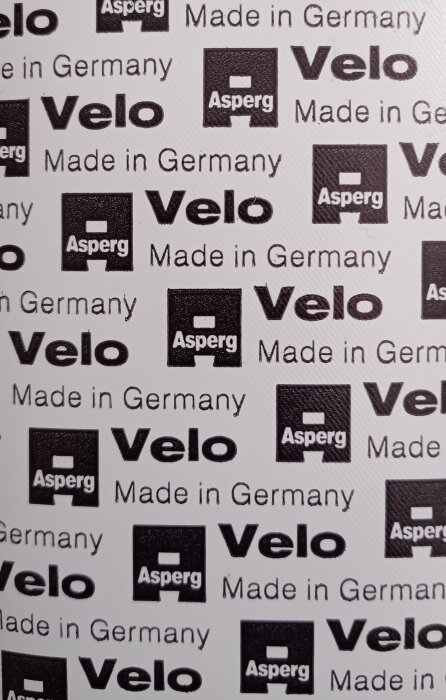 Mönster med texten "Asperg Velo Made in Germany" i svart på vit bakgrund, relaterat till cykellagningsmaterial.