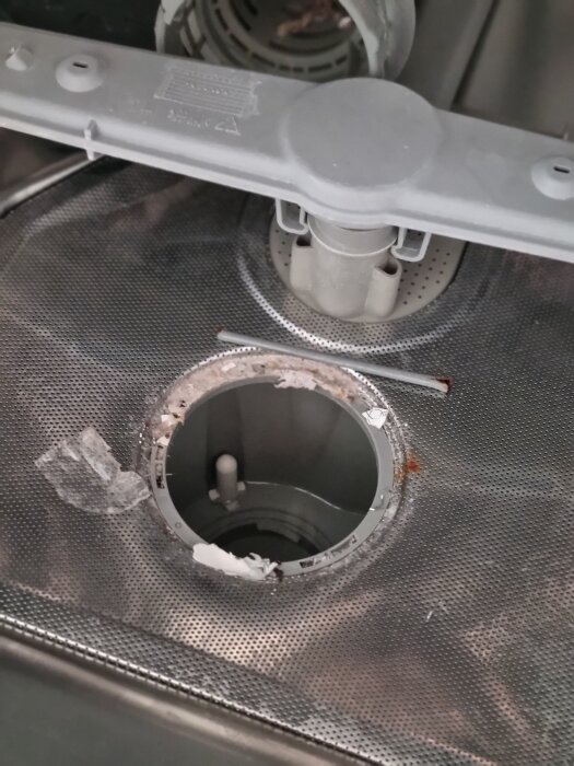 En öppen golvbrunn i en diskho med smuts och avlagringar runt kanten.