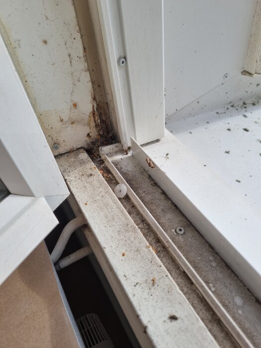 Smutsig fönsterkarm med damm och skräp, visar behov av rengöring.