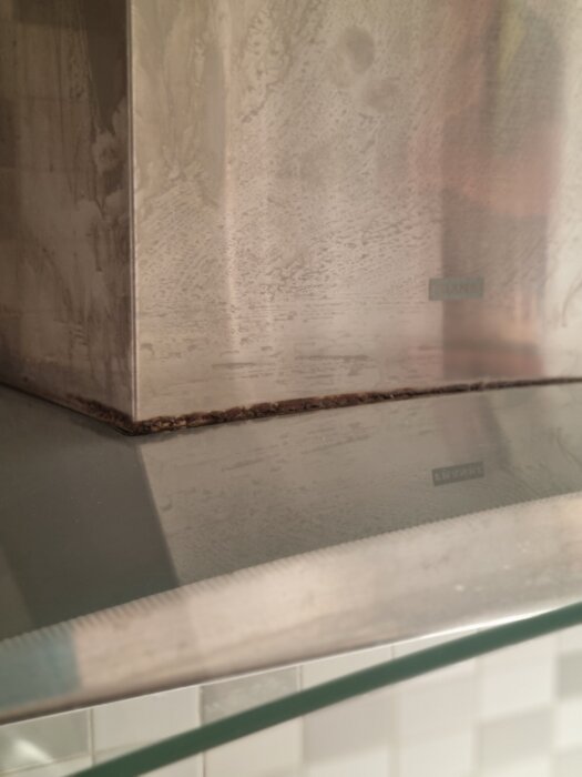 Bänkskiva med märken och smuts nära kant, del av diskussion om städfirman och ansvar för att rengöra ytan effektivt.