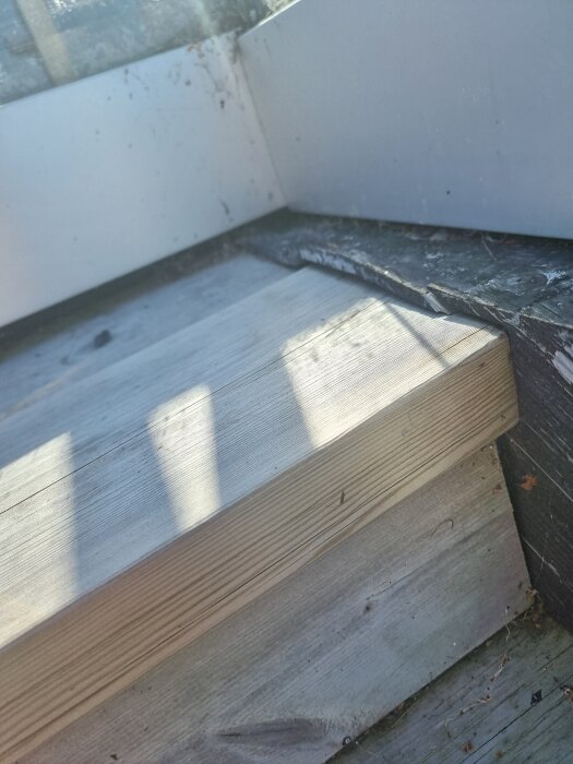 Trappa som har glidit och trycker mot en altan, visar ojämn placering vid en hörn. Trä och underliggande material ses nära en vägg.