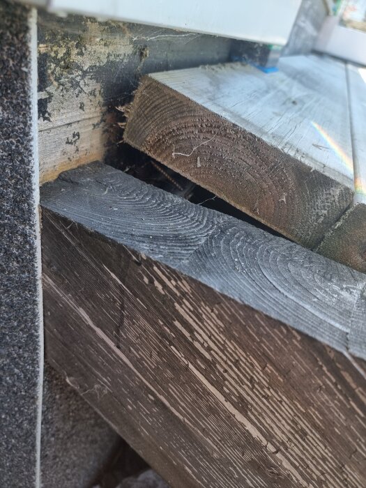 Trätrappa vid altan visar sneda brädor och avstånd mellan dem, med påverkad trästruktur och färg. Trappan verkar ha glidit.