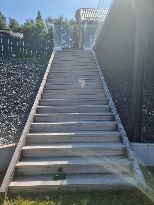 Trappa med trätrappsteg som leder från altanen ner till gräsmattan, omgiven av sten, synligt lutad och sned efter att ha glidit.