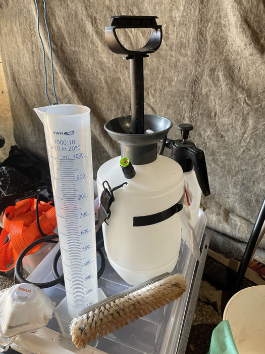 Tryckspruta, mätkärl och borste för fasadtvätt.