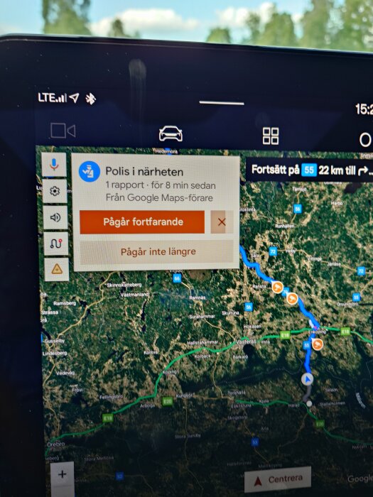 Navigationsskärm i en bil med karta och notifikation om polisrapport i närheten från Google Maps.