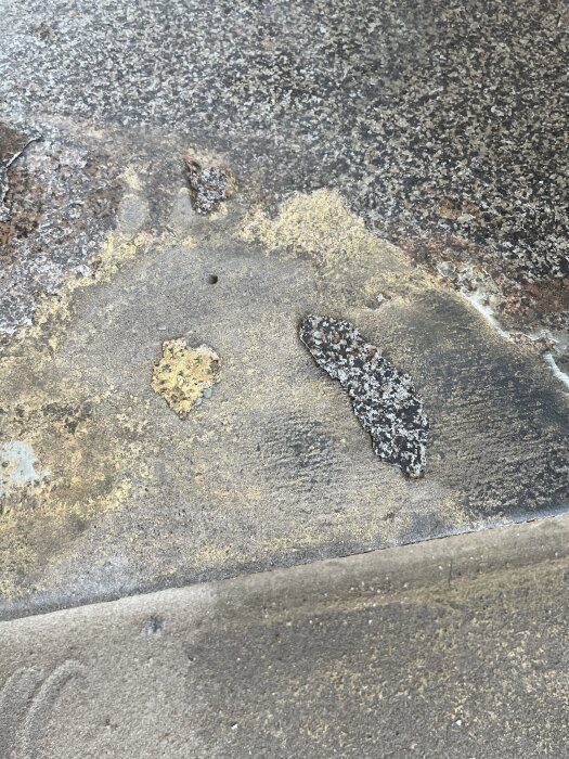 Sliten beläggning på betongtrappa, flagnar och avslöjar ytan under. Möjligen halkskydd, eventuellt epoxibaserad, ska tas bort vid renovering.