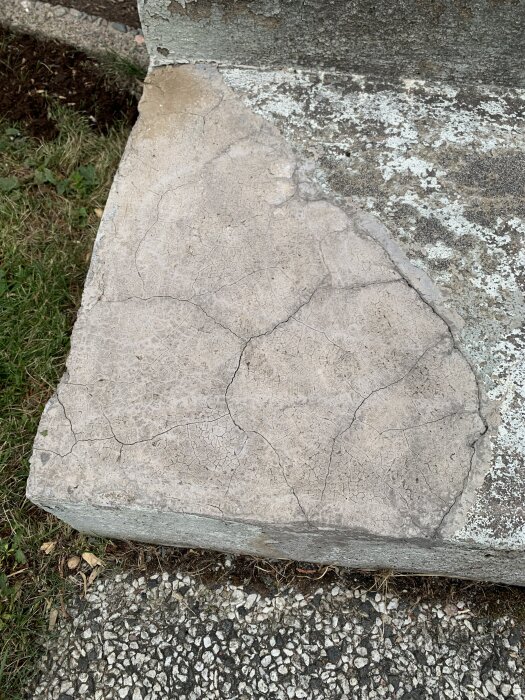 Gammal lagning med sprickor i en betongtrappa, omgiven av gräs och grus, behöver reparation innan målning.