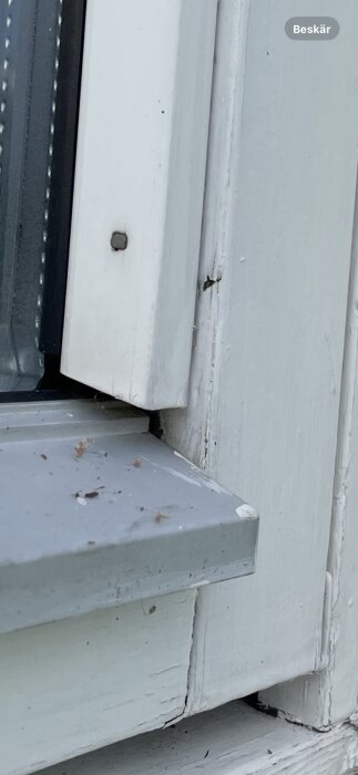 Närbild av insida på fönsterkarm med tecken på röta i träet, inkluderar sprickor och färgsläpp.