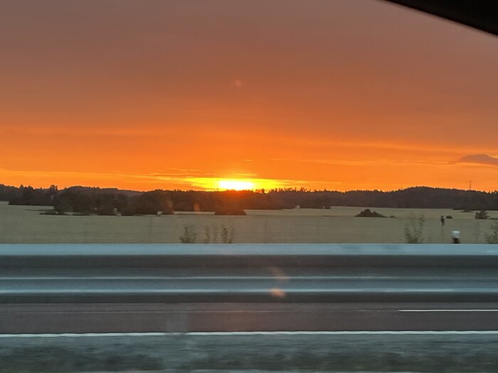 Solnedgång över landskap, sett från bilväg nära Nora.