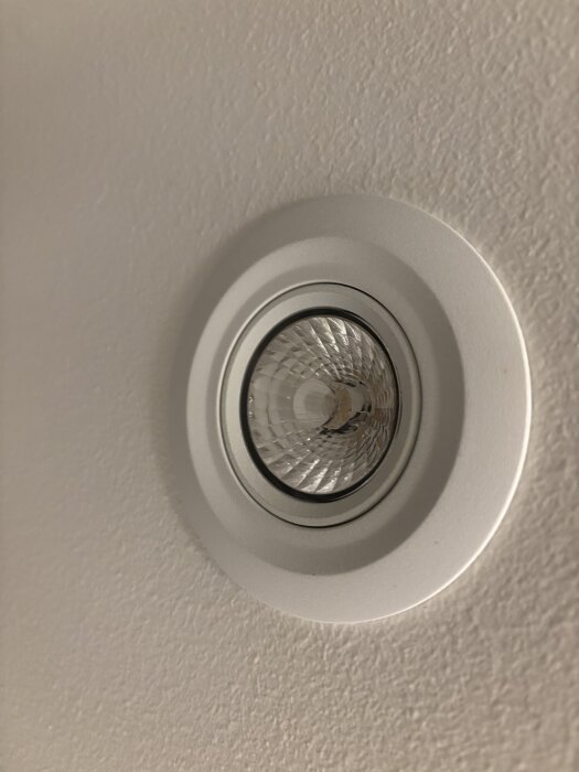 Inbyggd spotlight i tak, med fokus på linsen som kanske är gängad eller fungerar som ljusspridare.