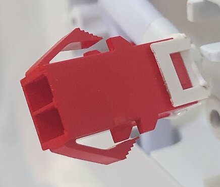 Röd och vit plastkontakt för anslutning av en 230 V led-lampa i en frysbox, visar både hona och hane delar.