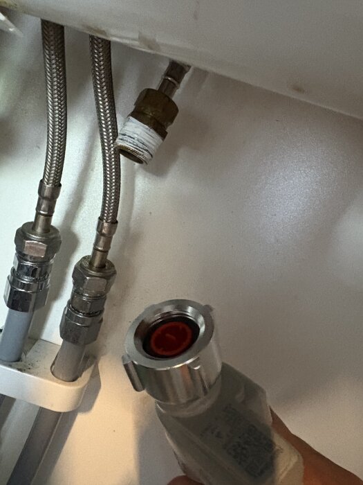Närbild av en okopplad röranslutning under en diskbänk, där ena sidan av kopplingen inte passar i fästet.