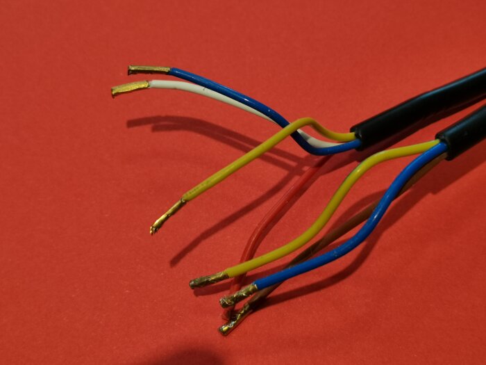 Flera lösa färgade kablar mot en röd bakgrund, avsedda för anslutning med en 8-pin kontakt till en fläkt.