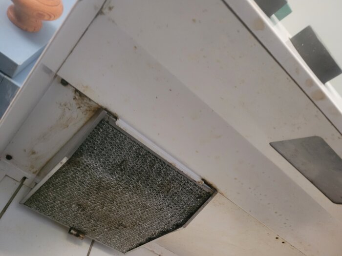 Närbild på undersidan av en spiskåpa med alliance-styrning från 1980-talet, med centralventilation och synligt smutsigt filter.