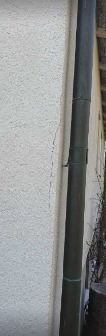 Spricka i husfasad från 1940-talet bredvid stuprör.