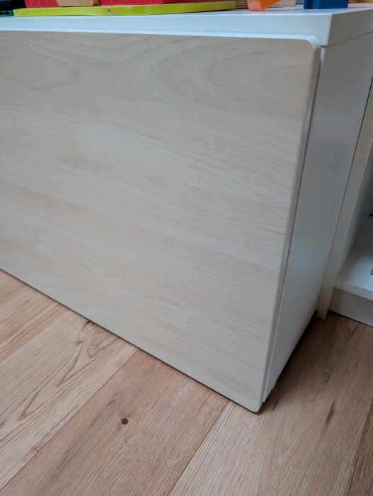 Träfärgad bänk med förvaring ovanpå trägolv, visar golvslitage efter två års användning.