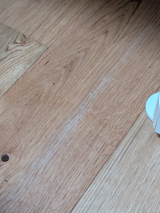 Golvet har märken och slitage bredvid en vit möbel, ett resultat av flitigt användande av bänkar med förvaring inspelade med leksaker.