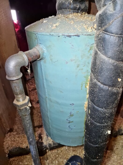 Äldre öppet expansionskärl med rostfläckar i ett självcirkulerande värmesystem från ca 1950. Bilden visar kärlets anslutningar och omgivning på vinden.