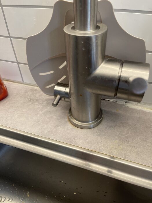 Köksblandare med vred i fel position på diskbänk, nära kakelvägg.