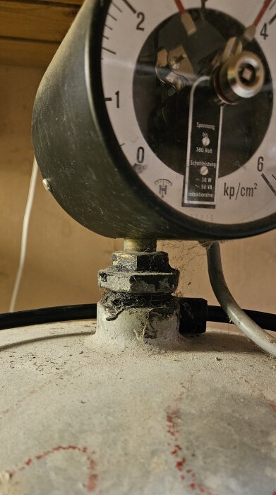 Tryckmätare monterad på en tank med rost och smuts.